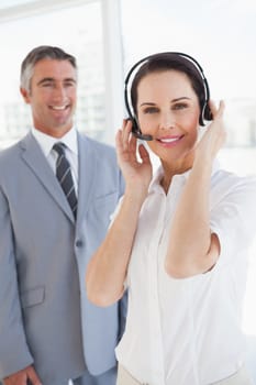 Businesswoman wearing a headset with co worker behind her