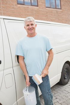 Portrait of smiling man with paint brush and tin in front of delivery van