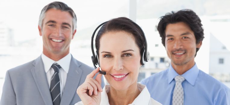 Businesswoman wearing her headset with co workers behind her
