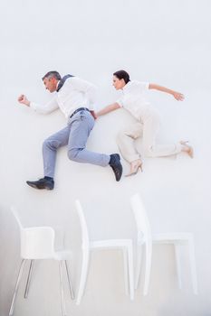 Business people jumping over some chairs 