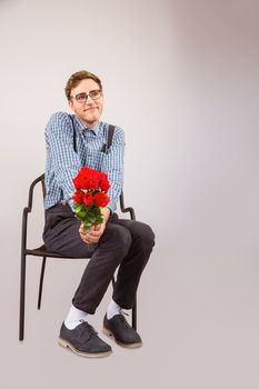 Geeky hipster holding a bunch of roses on grey background