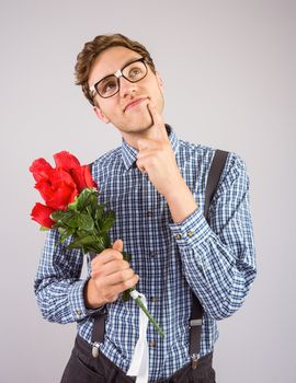 Geeky hipster holding a bunch of roses on grey background