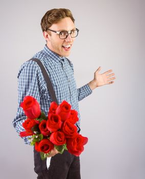 Geeky hipster holding a bunch of roses on grey background