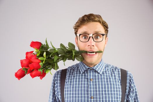 Geeky hipster biting a bunch of roses on grey background