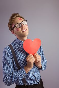 Geeky hipster covered in kisses on grey background