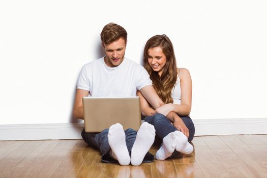 Full length of young couple sitting on floor and using laptop