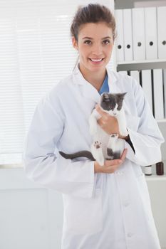 Smiling vet with a cute kitten in her arms in medical office