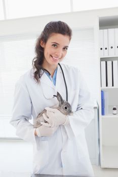 Smiling vet with a rabbit in her arms in medical office