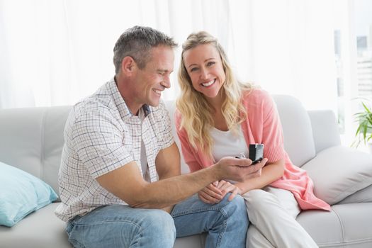 Man offering a romantic gift to his girlfriend at home in the living room