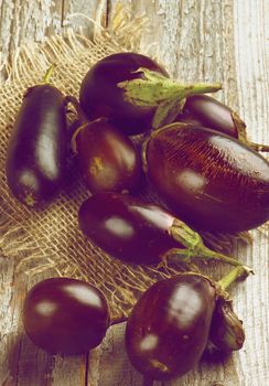 Fresh Ripe Small Eggplants on Sackcloth on Rustic Wooden background. Retro Styled