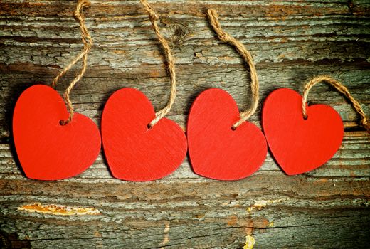Handmade Red Hearts with Ropes In a Row on Rustic Wooden background