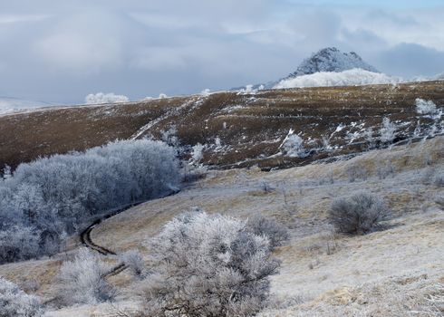 Rustic Road on Frosty Snowy Hills and Mount Beshtau on Cloudy Sky background Outdoors