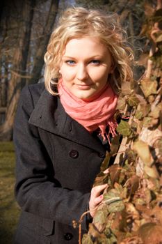 Beautiful young girl hiding behind a tree at fall.