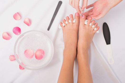 Beautician painting womans toenails at the beauty salon