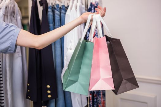 Woman holding shopping bags out in fashion boutique