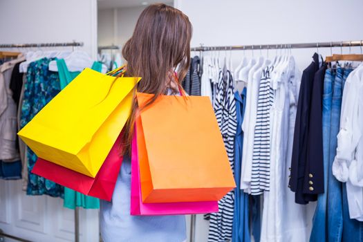 Woman holding shopping bags over shoulder in fashion boutique