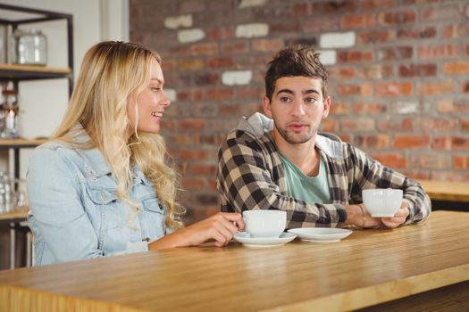 Smiling hipsters sitting and talking at coffee shop