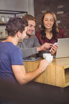 Smiling friends looking at smartphone at coffee shop