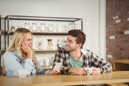 Smiling hipsters sitting and talking at coffee shop