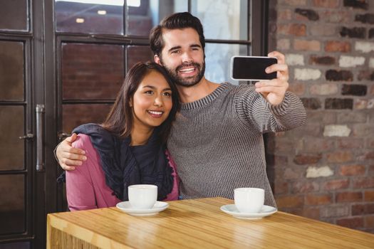 Young happy couple making a selfie in the cafe