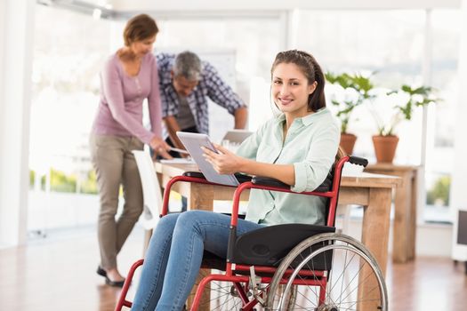 Portrait of casual businesswoman in wheelchair using tablet in the office