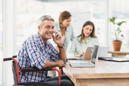 Portrait of casual businessman in wheelchair phoning in the office