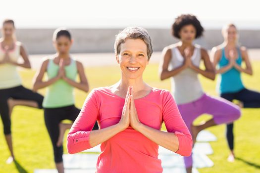 Portrait of smiling sporty woman doing yoga in yoga class in parkland
