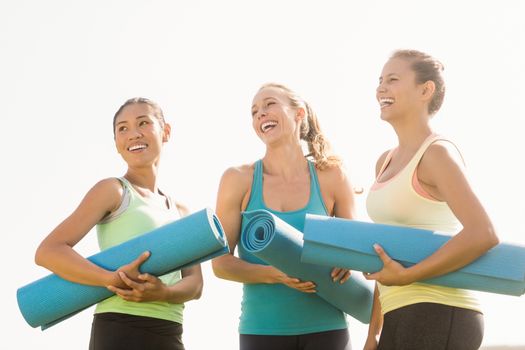 Laughing sporty women with exercise mats in parkland