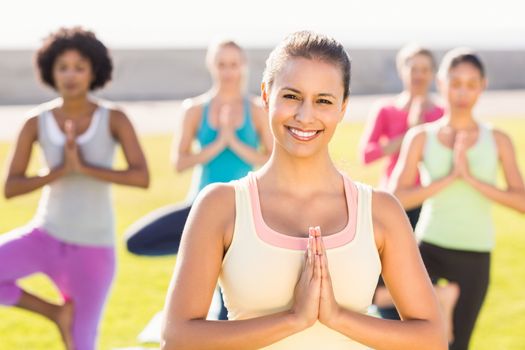 Portrait of smiling sporty brunette doing yoga in yoga class in parkland
