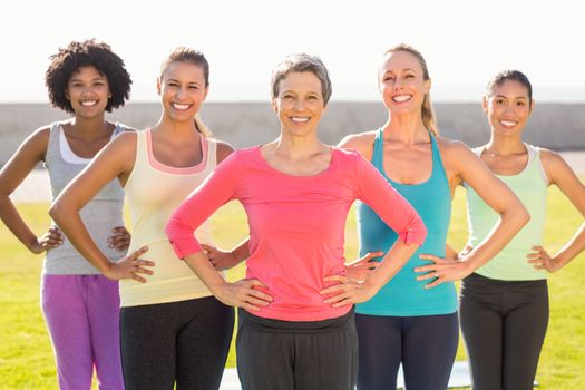 Portrait of smiling sporty women with hands on hips in parkland