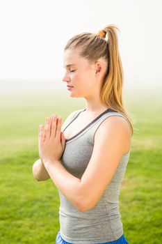 Peaceful sporty blonde meditating in parkland