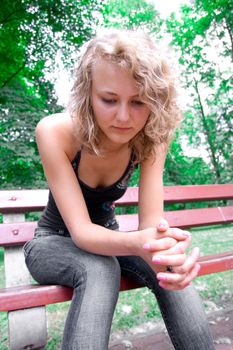 Young depressed girl sitting on a park bench.