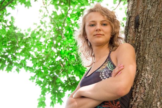 Young beautiful girl based on the tree and smiles.