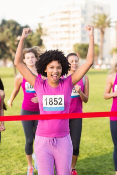 Portrait of cheering young woman winning breast cancer marathon in parkland