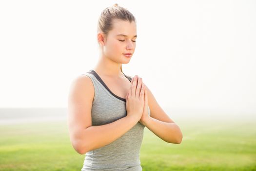 Peaceful sporty blonde meditating in parkland