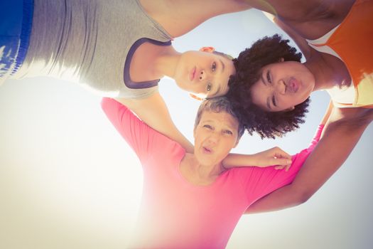 Portrait of sporty women with arms around posing down to camera at promenade