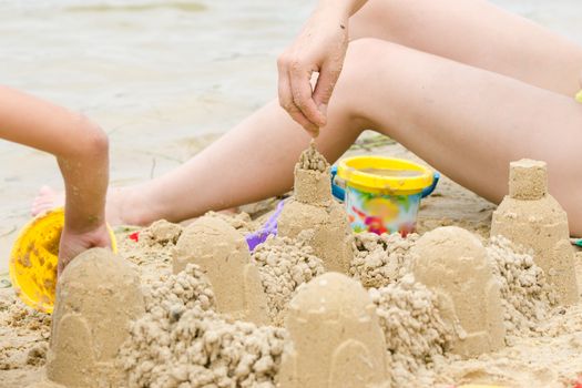 Mom and daughter on the banks of the river builds a sand castle