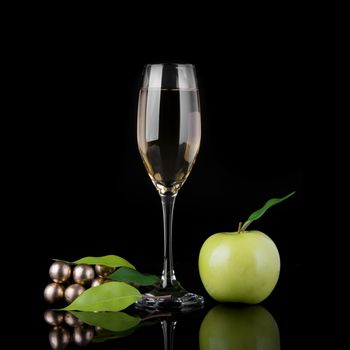 Green apple with a glass of champagne on black background