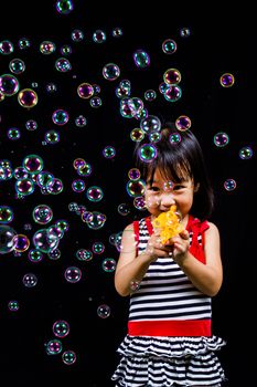 Asian Chinese children Playing Soap Bubbles in black background indoor.