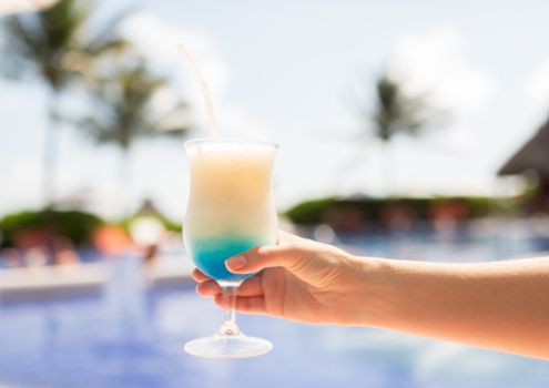 vacation, beverage and travel concept - close-up of female hand holding glass with cocktail