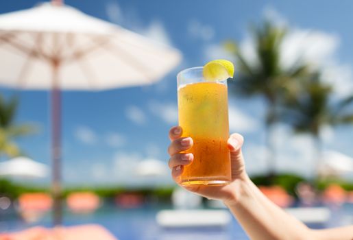 vacation, beverage and travel concept - close-up of female hand holding glass with cocktail