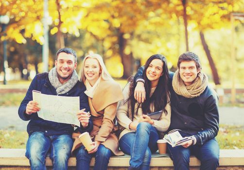 holidays and tourism concept - group of friends or couples with tourist map in autumn park