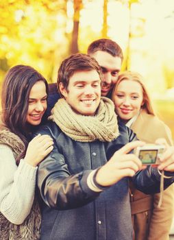 holidays, vacation, travel and tourism concept - group of friends or couples having fun in autumn park and taking selfie