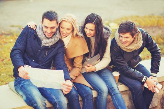 holidays and tourism concept - group of friends or couples with tourist map in autumn park