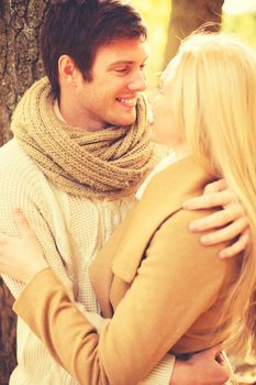 holidays, love, relationship and dating concept - romantic couple kissing in the autumn park