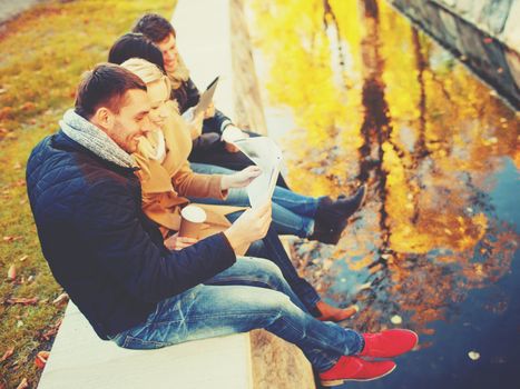 holidays and tourism, navigation concept - group of friends or couples with tourist map and tablet pc computer in autumn park