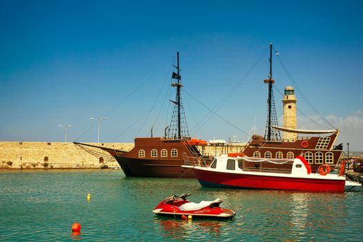 Views of the port , Rethymno city, Crete, Greece. There are multiple ships in the harbour, pier, lighthouse.