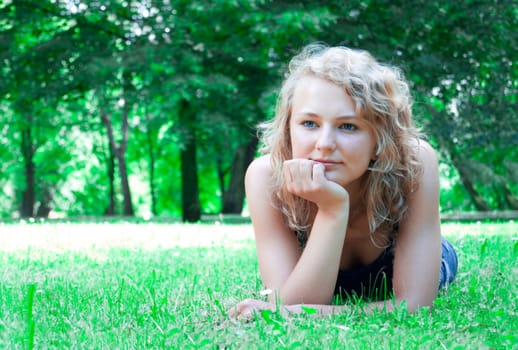 Young beautiful girl lies on the lawn and thinking about the future.