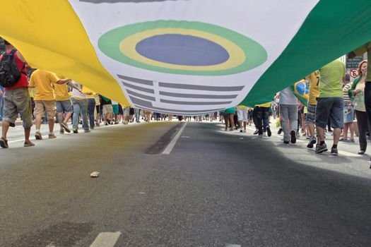 SAO PAULO, BRAZIL August 16, 2015: An unidentified group of people hold a big flag in the protest against federal government corruption in Sao Paulo Brazil. Protesters call for the impeachment of President Dilma Rousseff.