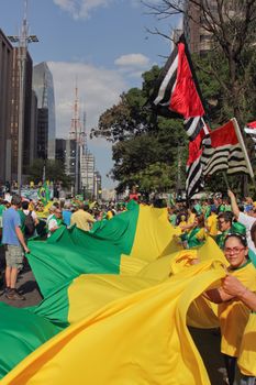 SAO PAULO, BRAZIL August 16, 2015: An unidentified group of people hold a big flag in the protest against federal government corruption in Sao Paulo Brazil. Protesters call for the impeachment of President Dilma Rousseff.